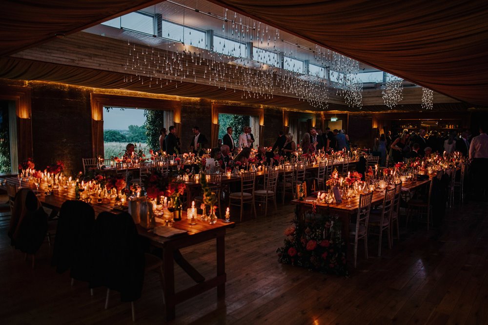 Big wedding reception venue with hundreds of candles lit on long tables for a romantic and atmospheric wedding party in Gloucester