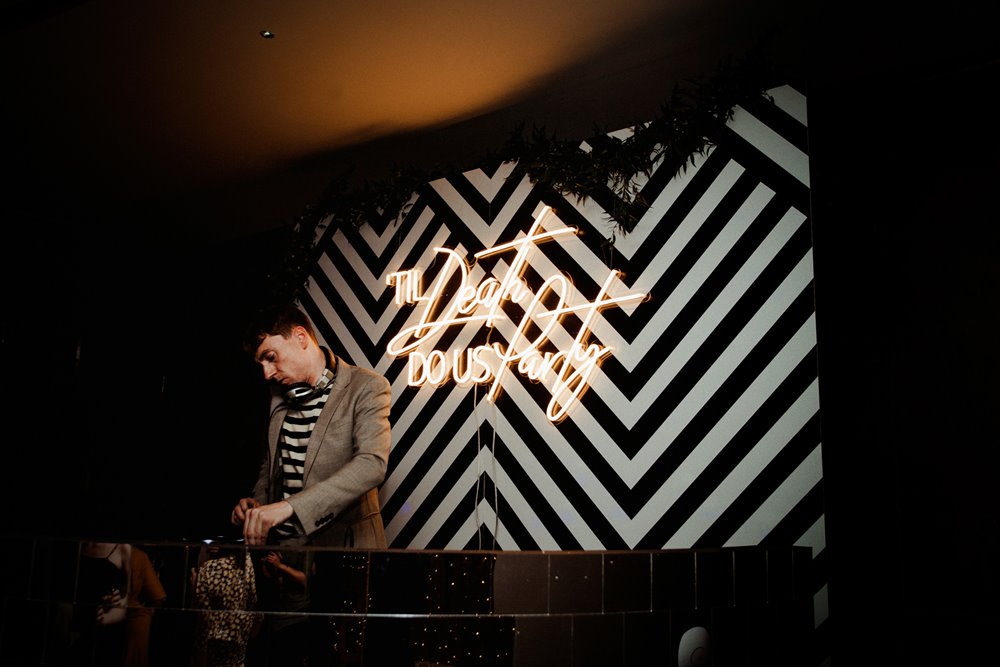 DJ plays in front of Till death do us party sign at a late night wedding party in the UK