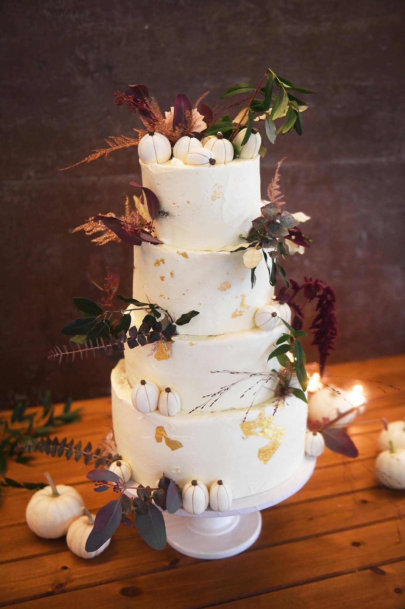 Pumpkin wedding cake with 4 tiers of flavours including pumpkin spice decorated with autumnal foliage and mini fondant pumpkins for an October wedding