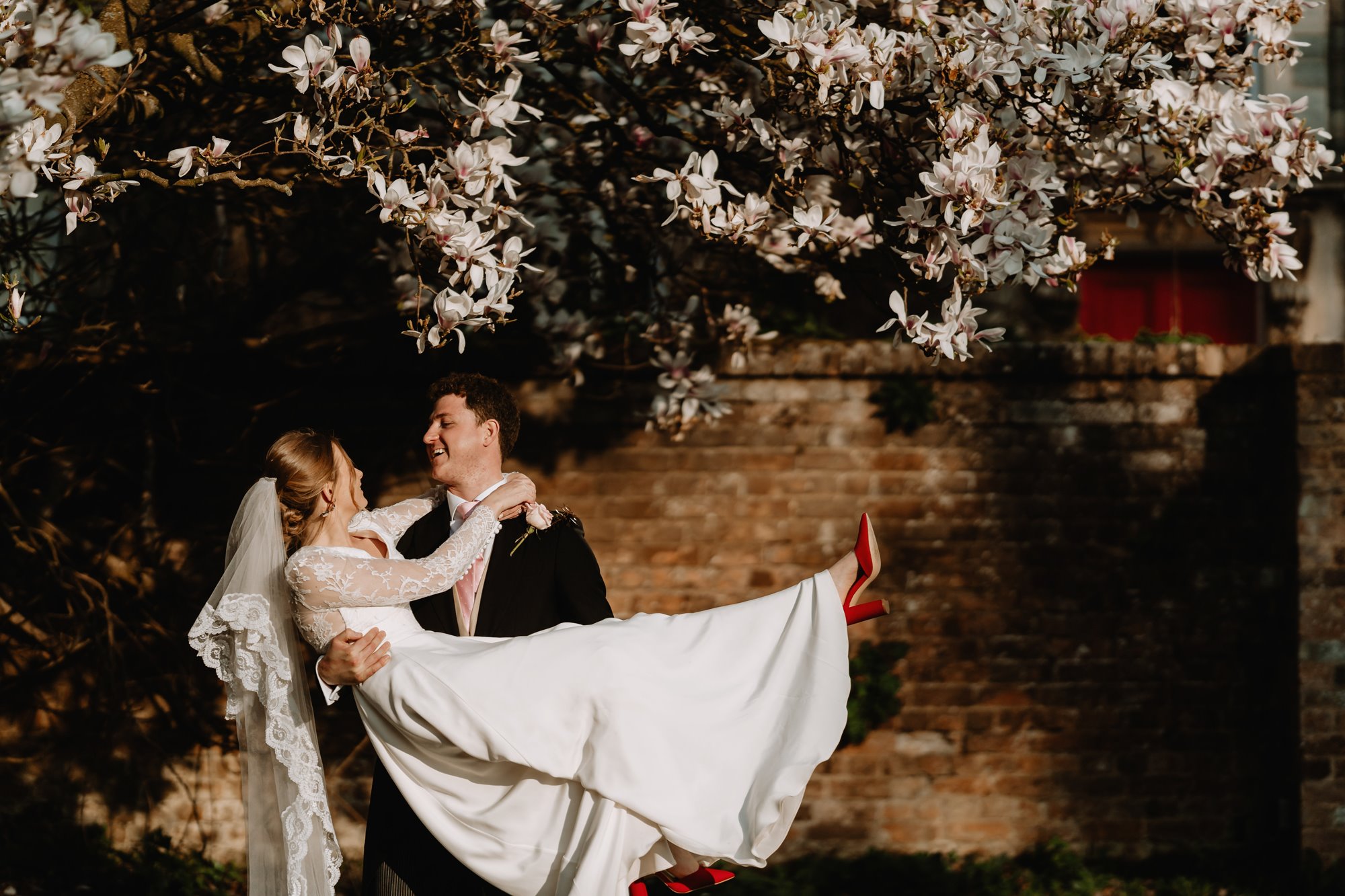 a groom carrying his new wife outside of s stately home in Gloucestershire 