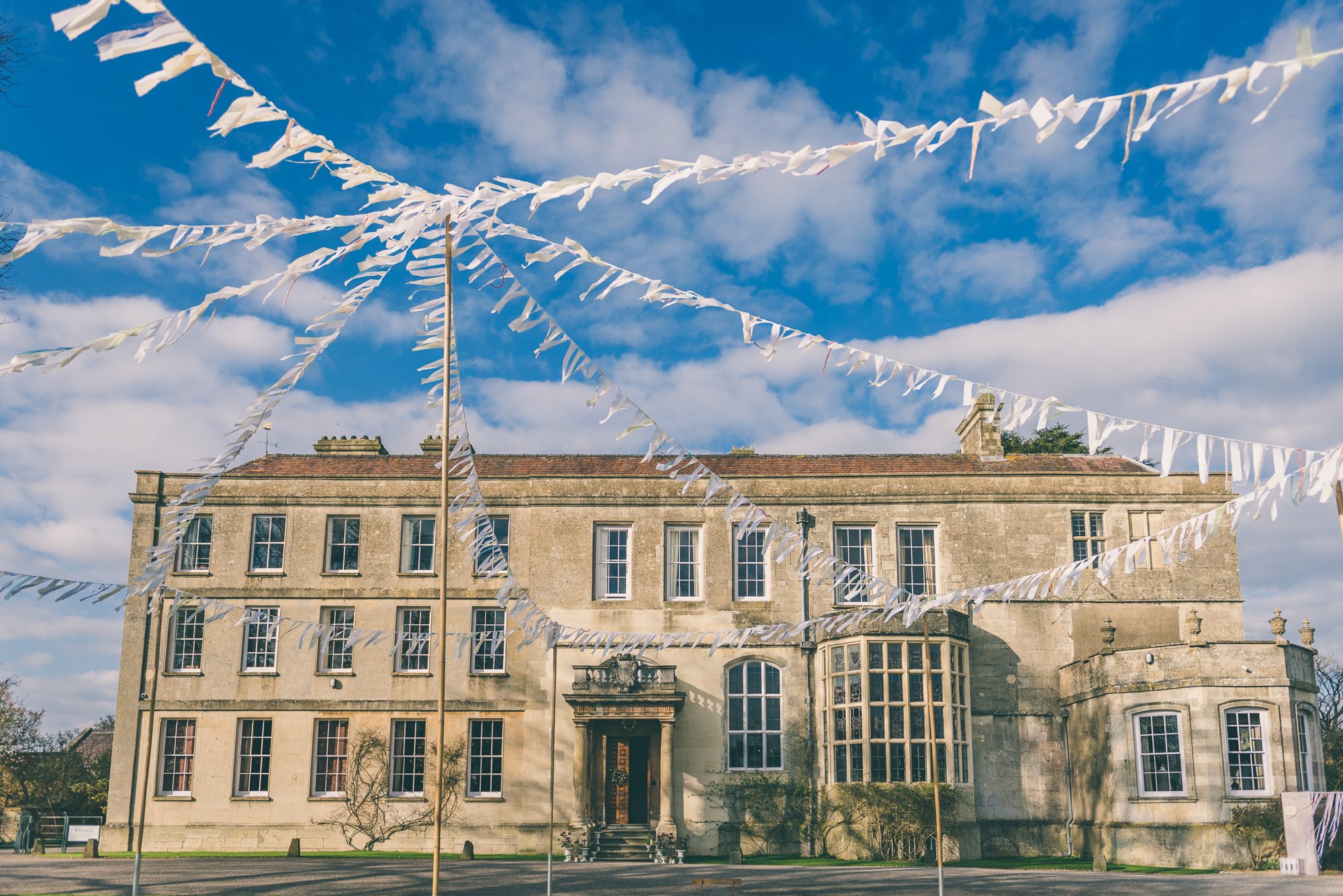 Bunting on poles outside the front of mansion house elmore court for a jubilee tea party inspired garden wedding 