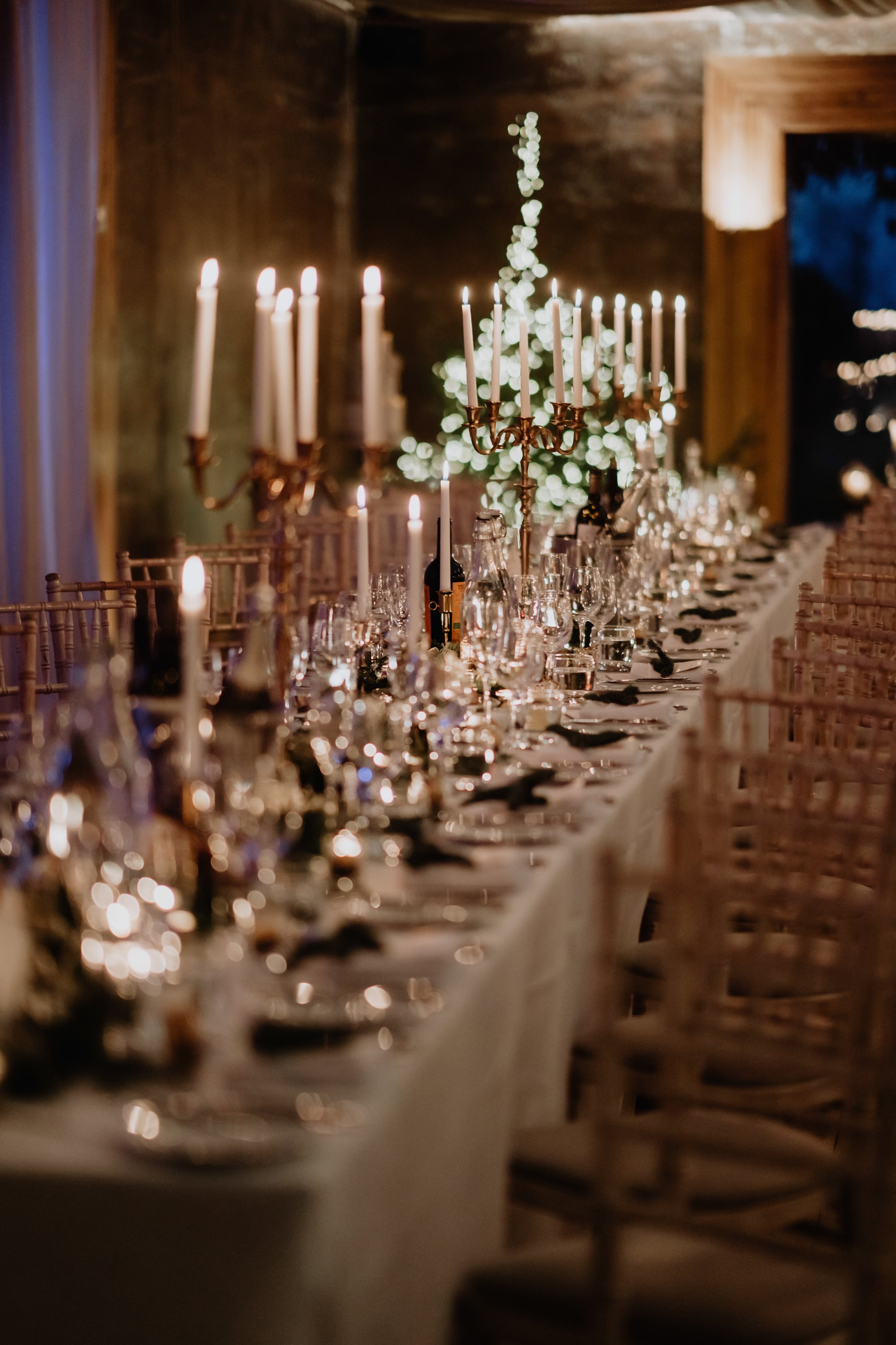 wedding reception tables styled with tall white candles in copper candelabras