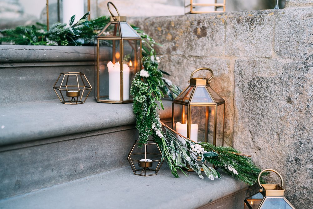 Christmas lanterns with green foliage decorating the steps of wedding venue for a Christmas wedding