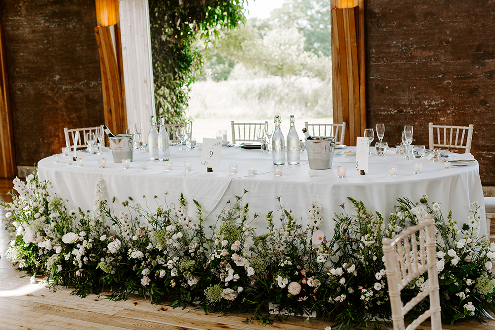 Unusual Wild greenery and floral top table decor around the bottom of wedding table for a wild boho wedding at ELmore court in the cotswolds