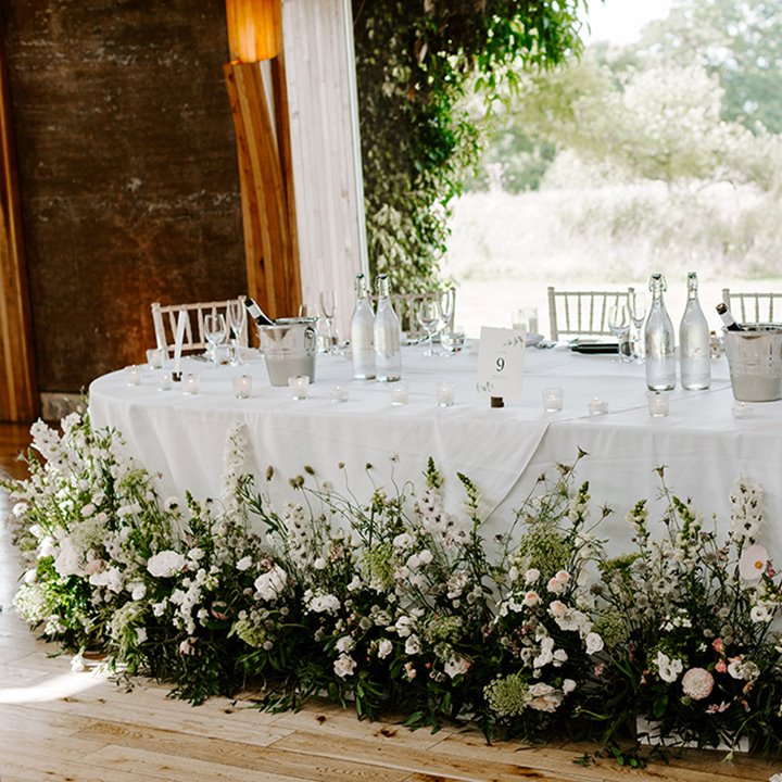 Unusual Wild greenery and floral top table decor around the bottom of wedding table for a wild boho wedding at ELmore court in the cotswolds