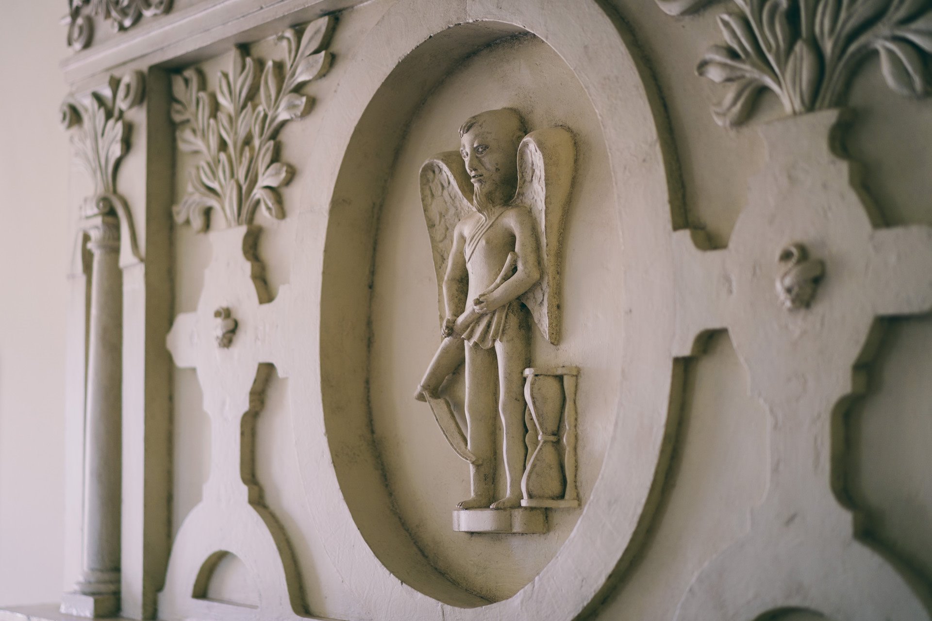 Depiction of Father Time with scythe and hourglass in the fireplace of the time bedroom at wedding venue Elmore Court in Gloucestershire