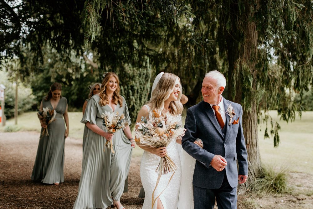 Bride and father walk towards church excitedly on wedding day