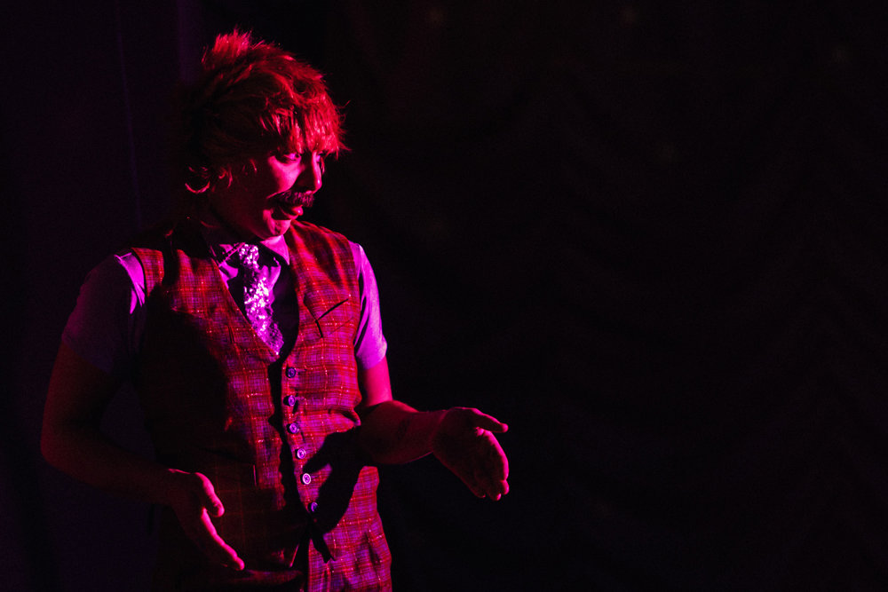 Jess love drag king on stage under red lights at elmore court's pop up covid cabaret