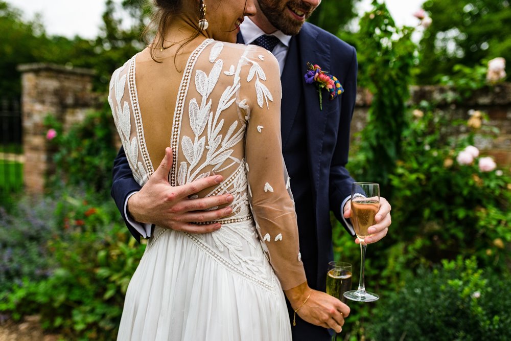 Bride wears Stunning floral patterned french lace wedding gown in the walled garden at elmore court