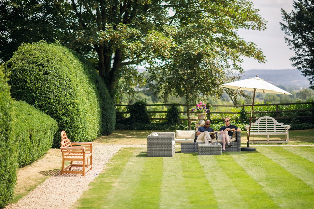 Guests relaxing on outdoor furniture at gay garden party wedding in the summer