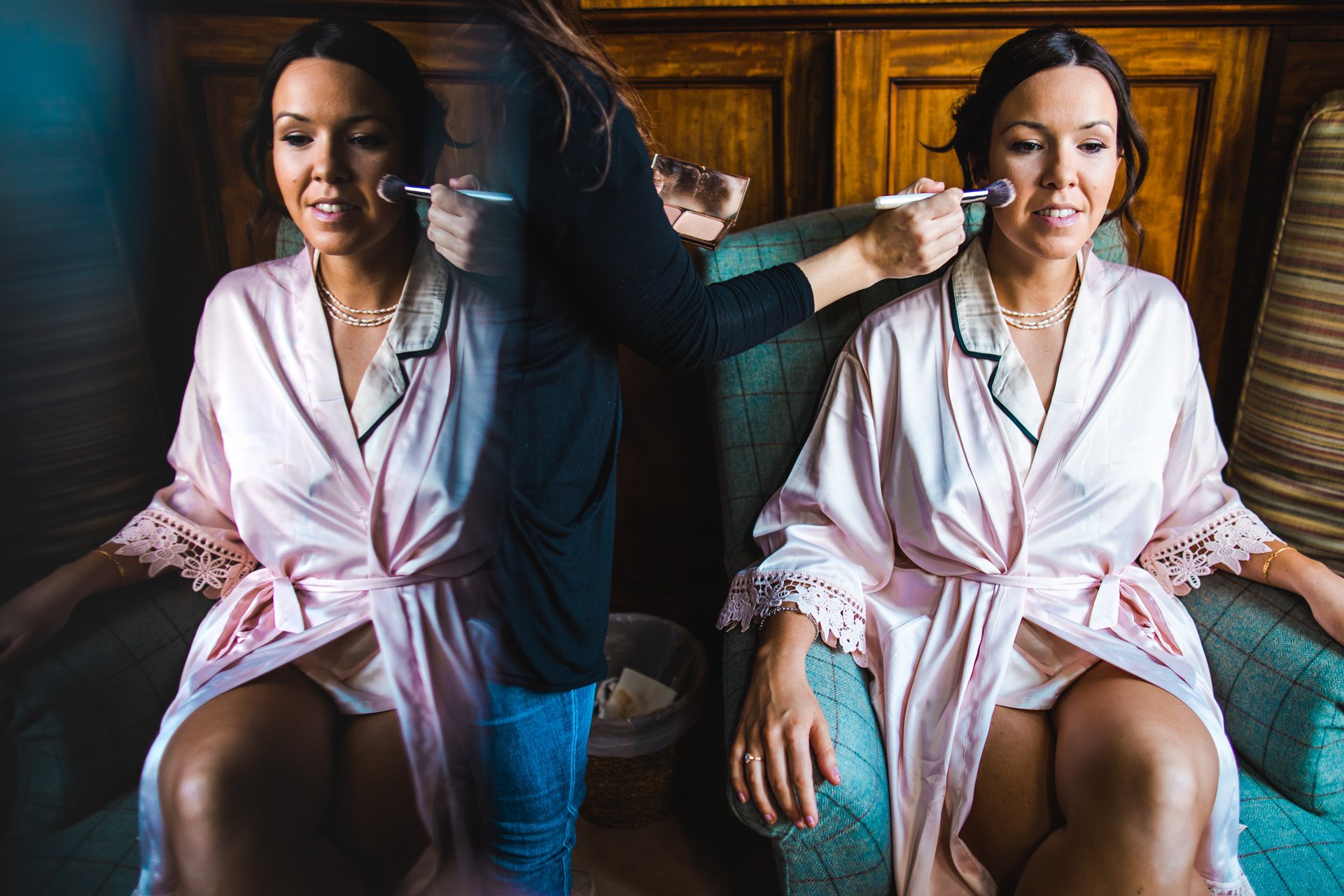 Bride having makeup applied in personalised dressing gown on morning of weekend long wedding