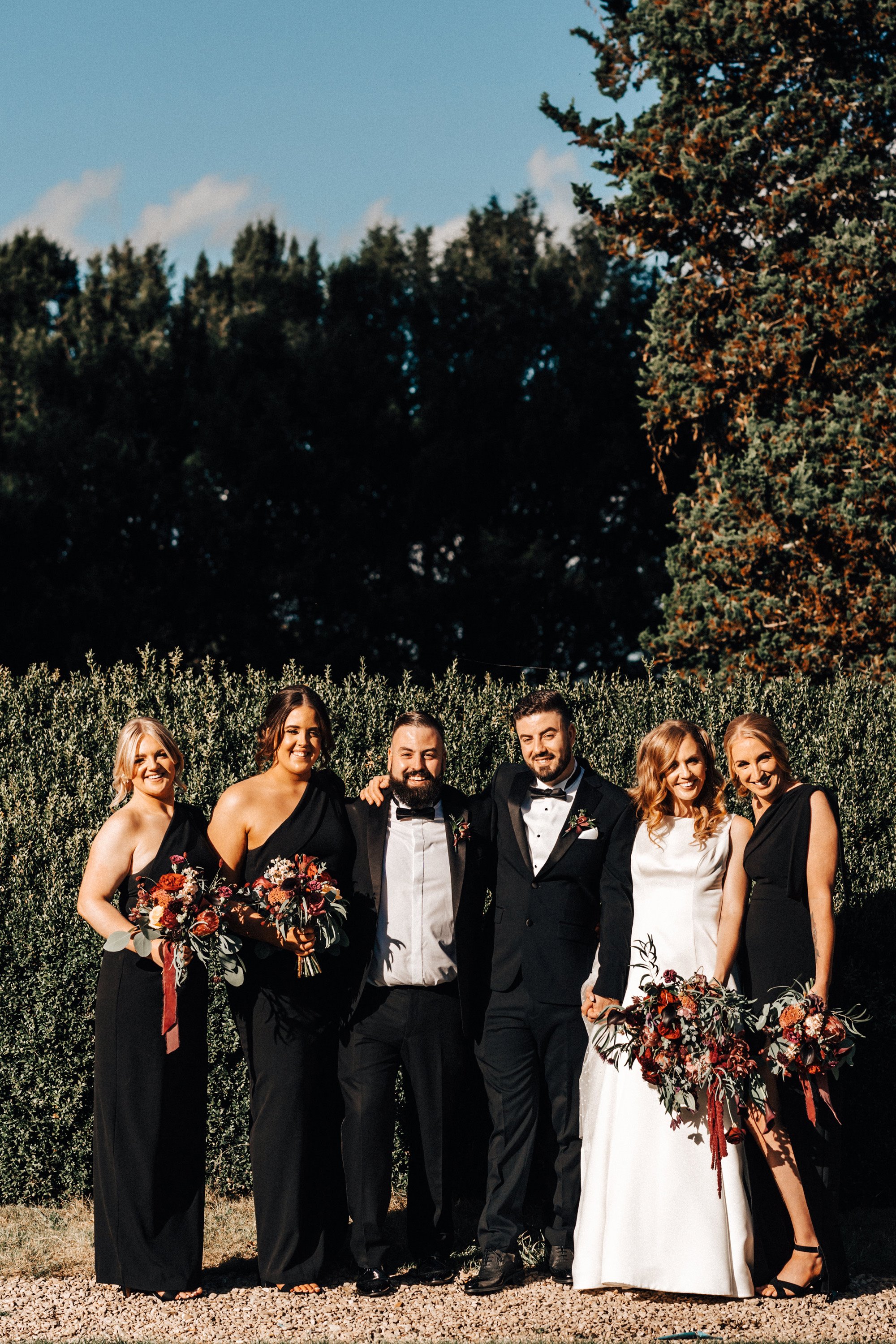 bridesmaids in black dresses and groomsmen in black tuxedos for a relaxed black tie autumn wedding with black accents in the cotswolds