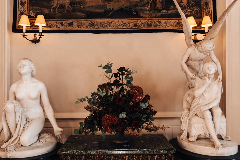 winter wedding flowers between angel statues for christmas wedding ceremony at manor house