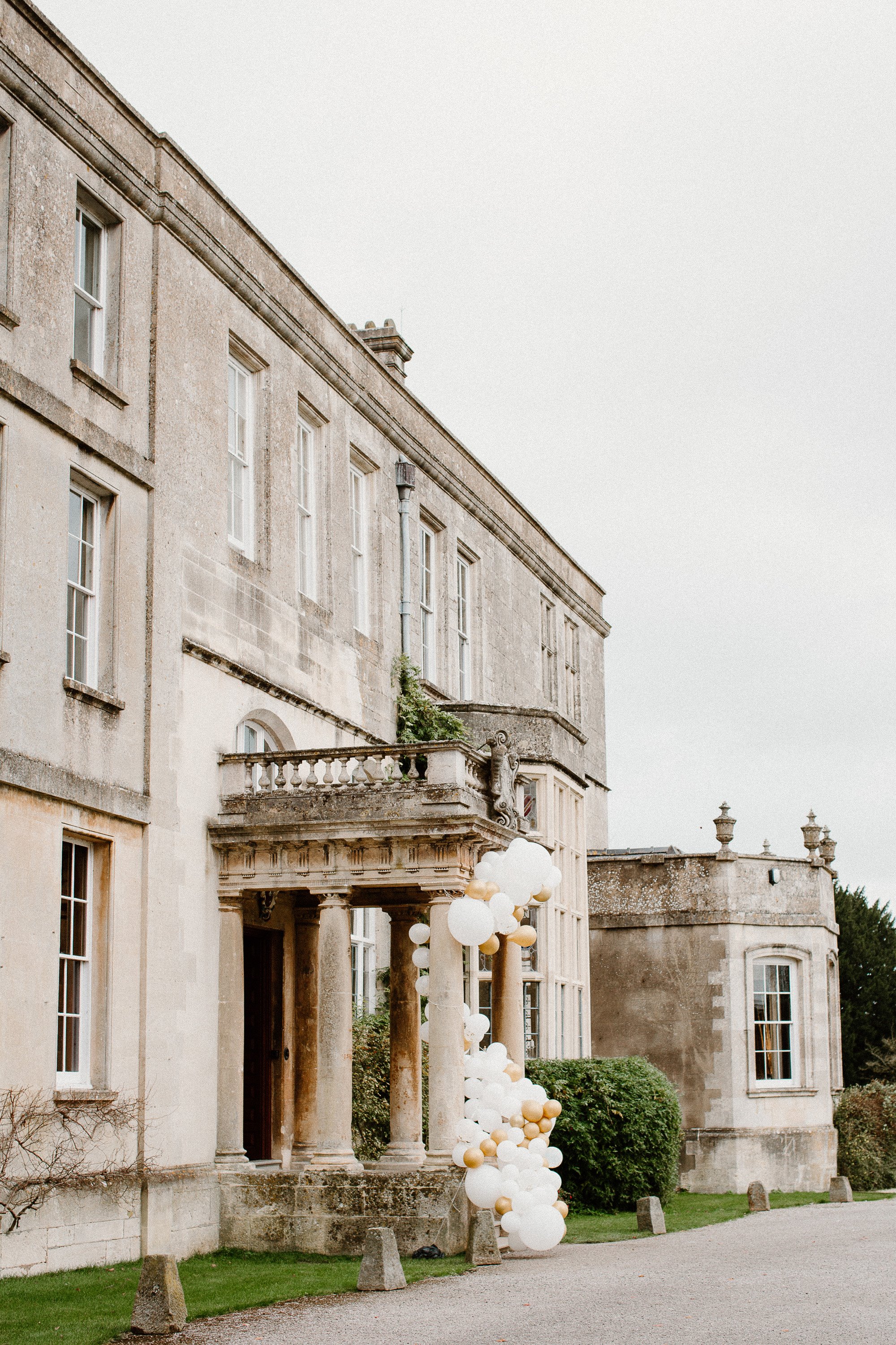 Balloons that look like pearls decorating the front of mansion house wedding venue elmore court in the cotswolds