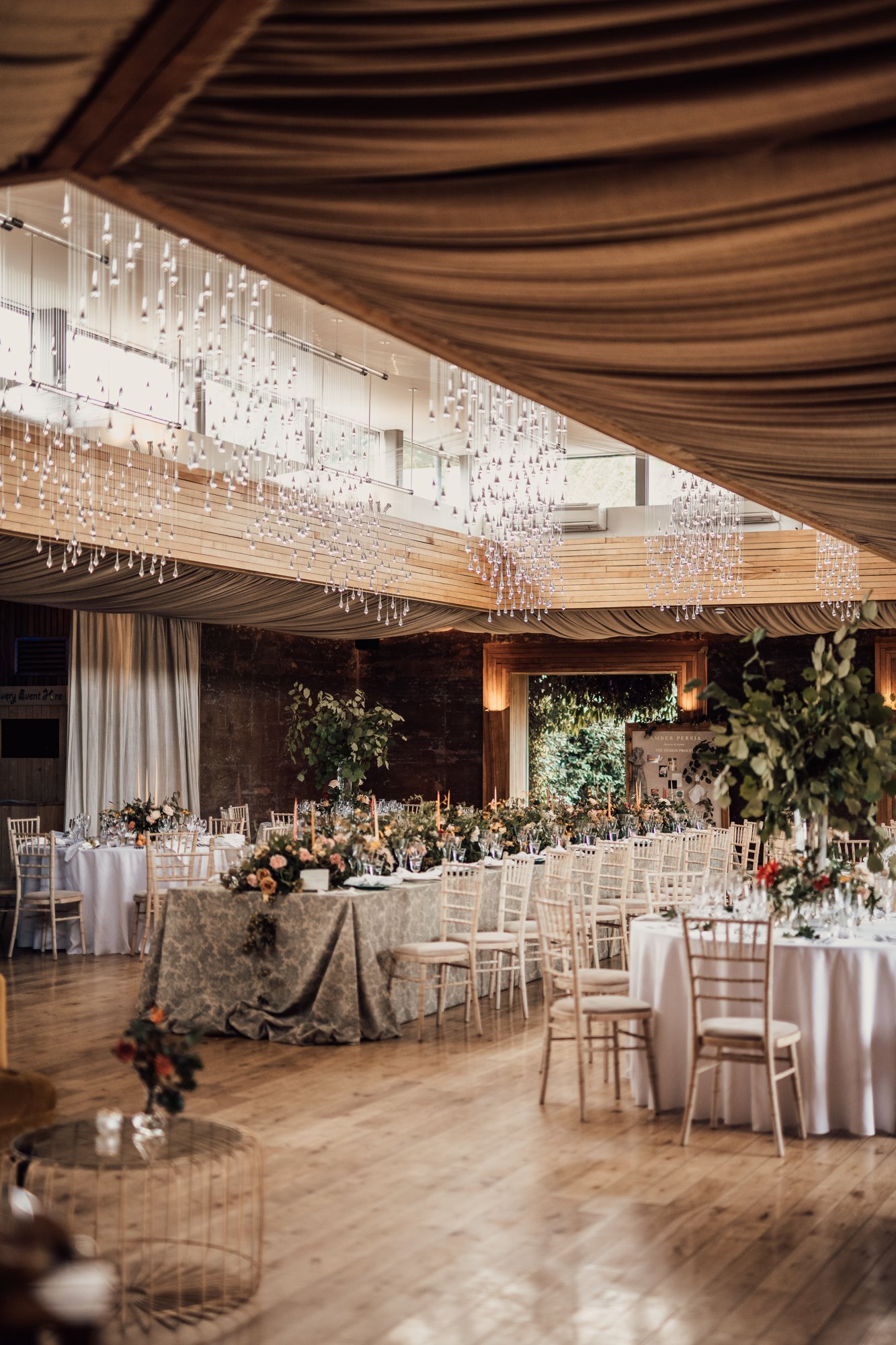 Beautiful Wedding reception with light installation decorated with september florals and fruits on a mix of long and round tables for a wild wedding fair Harvestival at elmore court in Gloucestershire