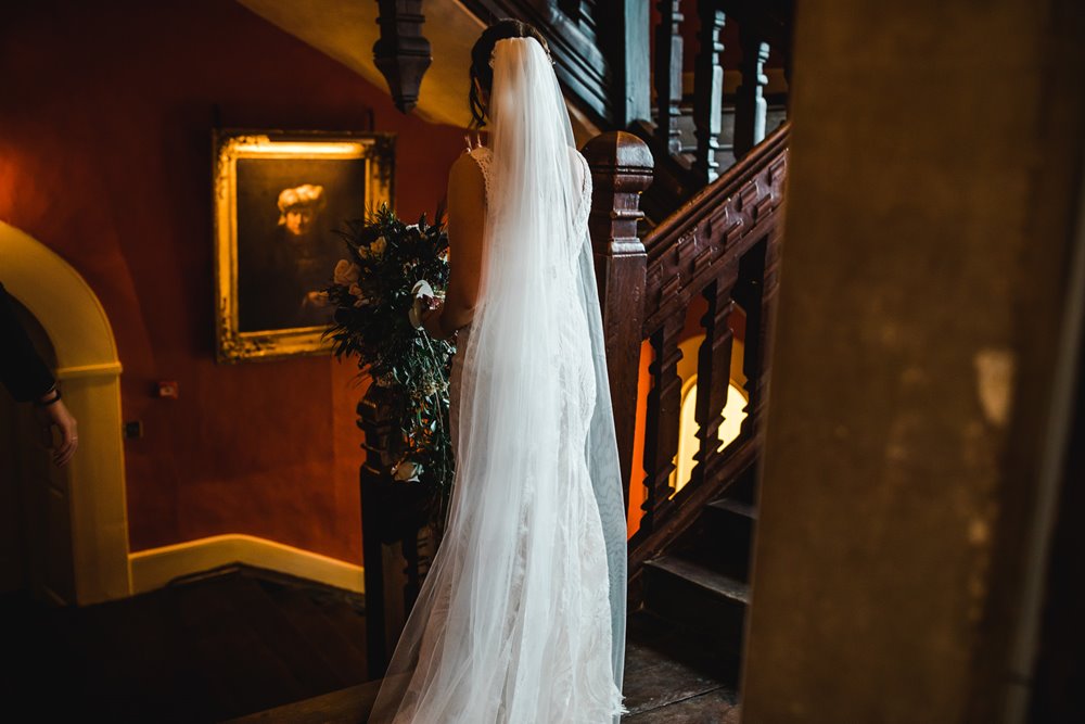 Bride wearing cathedral length veil in the 500 year old hall of mansion house elmore court