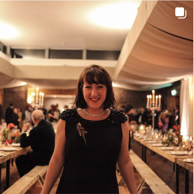 Wedding coordinator smiling in front of dining guests with candles on long tables at cotswolds eco wedding venue as it first opened back in 2013