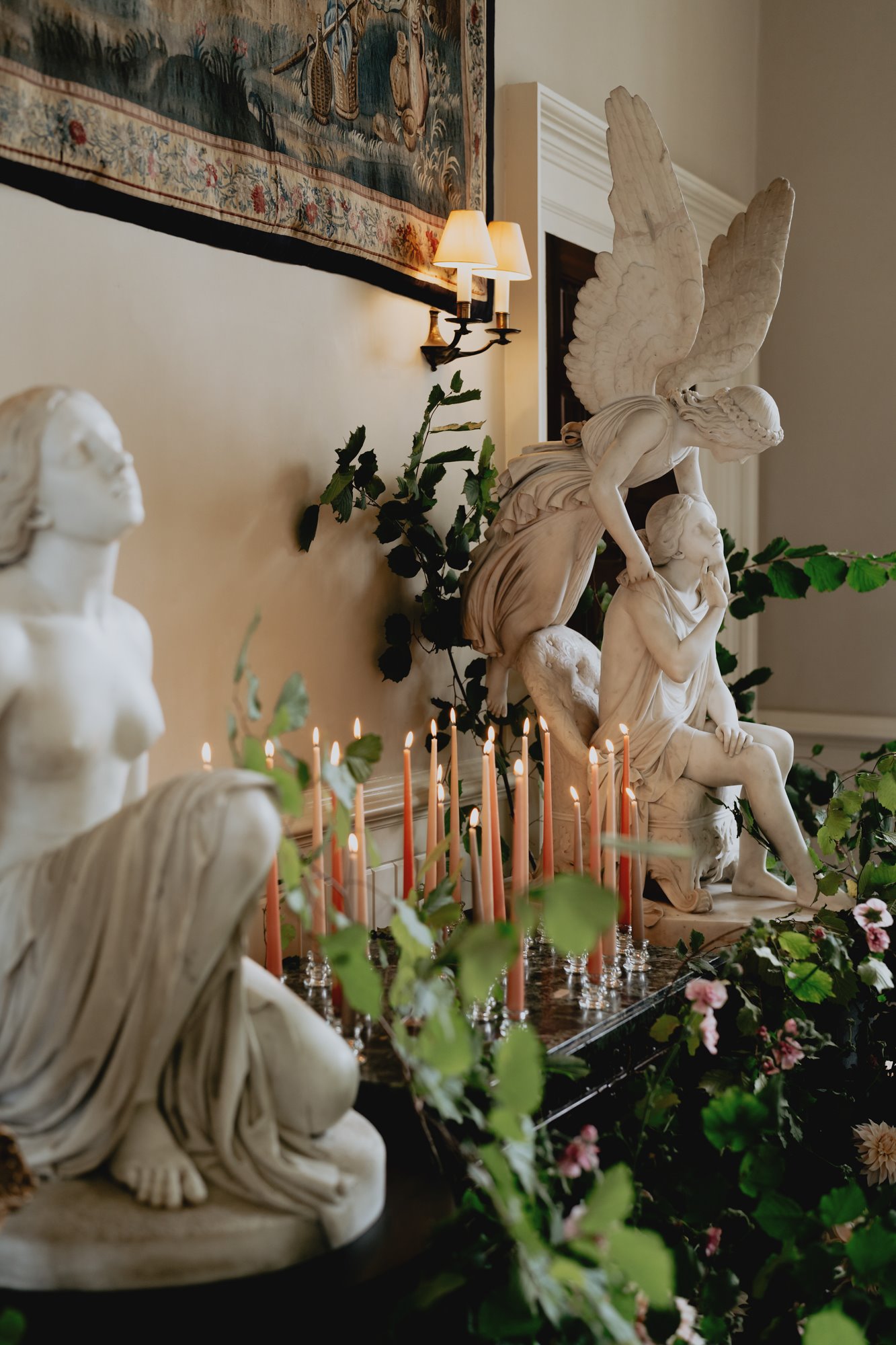Elegant wedding venue with angel statues decorated with pink candlesticks and trailing greenery in the Cotswolds