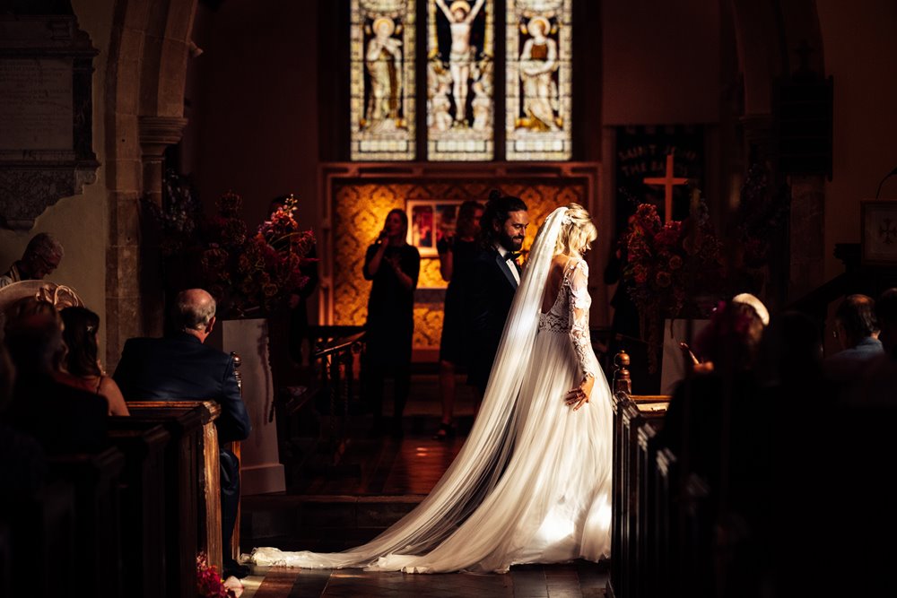beautiful boho bride and groom in atmospheric wedding ceremony in a beautiful church in england