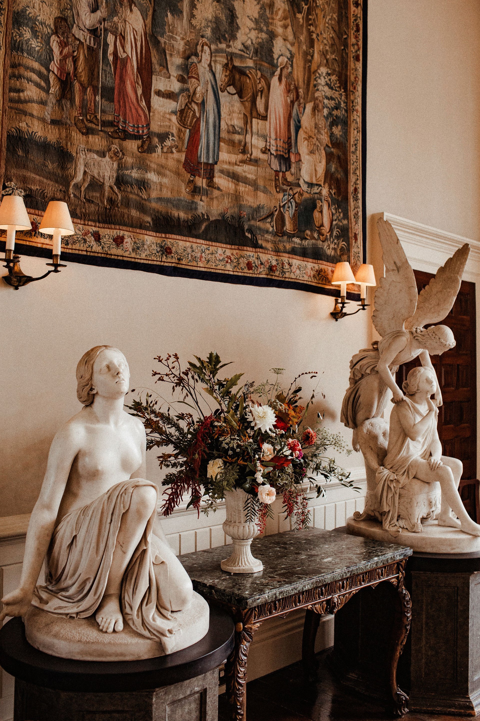 Autumn wedding ceremony decor of flowers and angel statues at stately home in the cotswolds